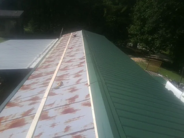 Old rusted panels beside newly installed green metal roofing — Wind Damage Roof Repair by Roofing Brothers in Leadville