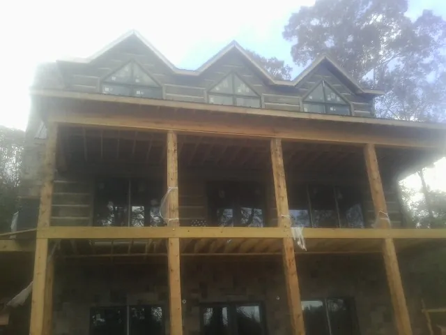 Dormers and porch framing on a large log home under construction — Roof Coating work by our crew in Leadville