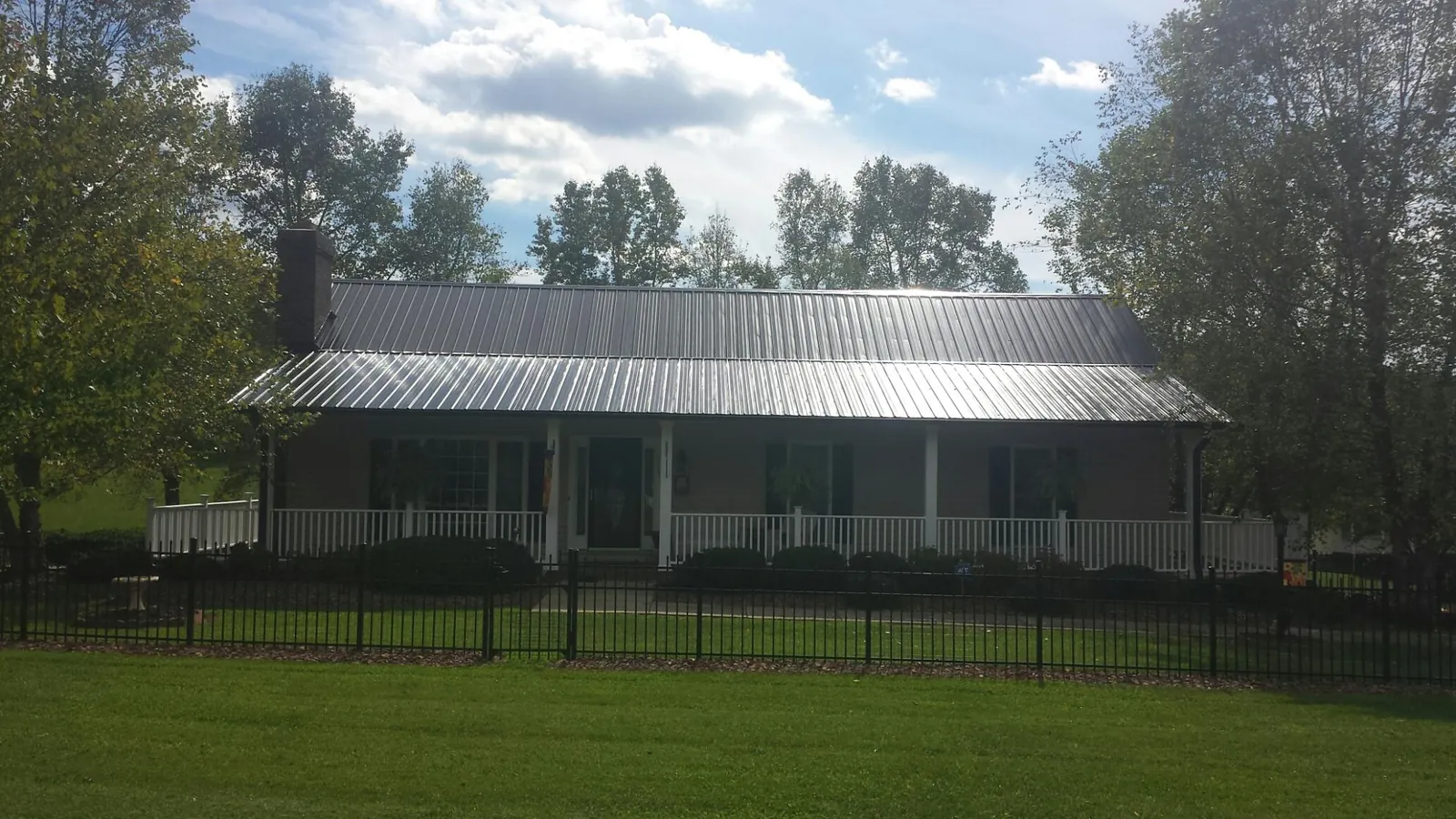 Gray metal roof on a brick ranch with a full width front porch — Gutter Guard Installation work by our crew in Leadville