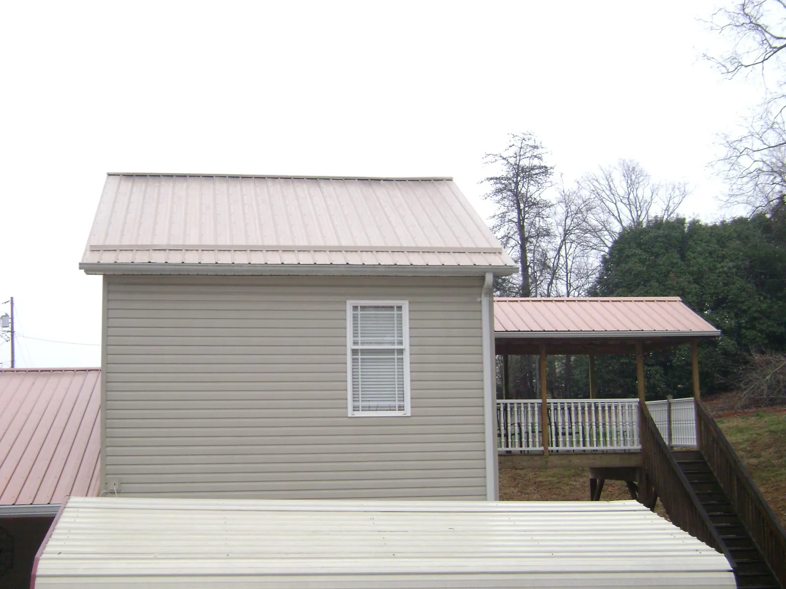 Tan metal roofs on a two story addition and attached porch, from a Roof Replacement job in Leadville