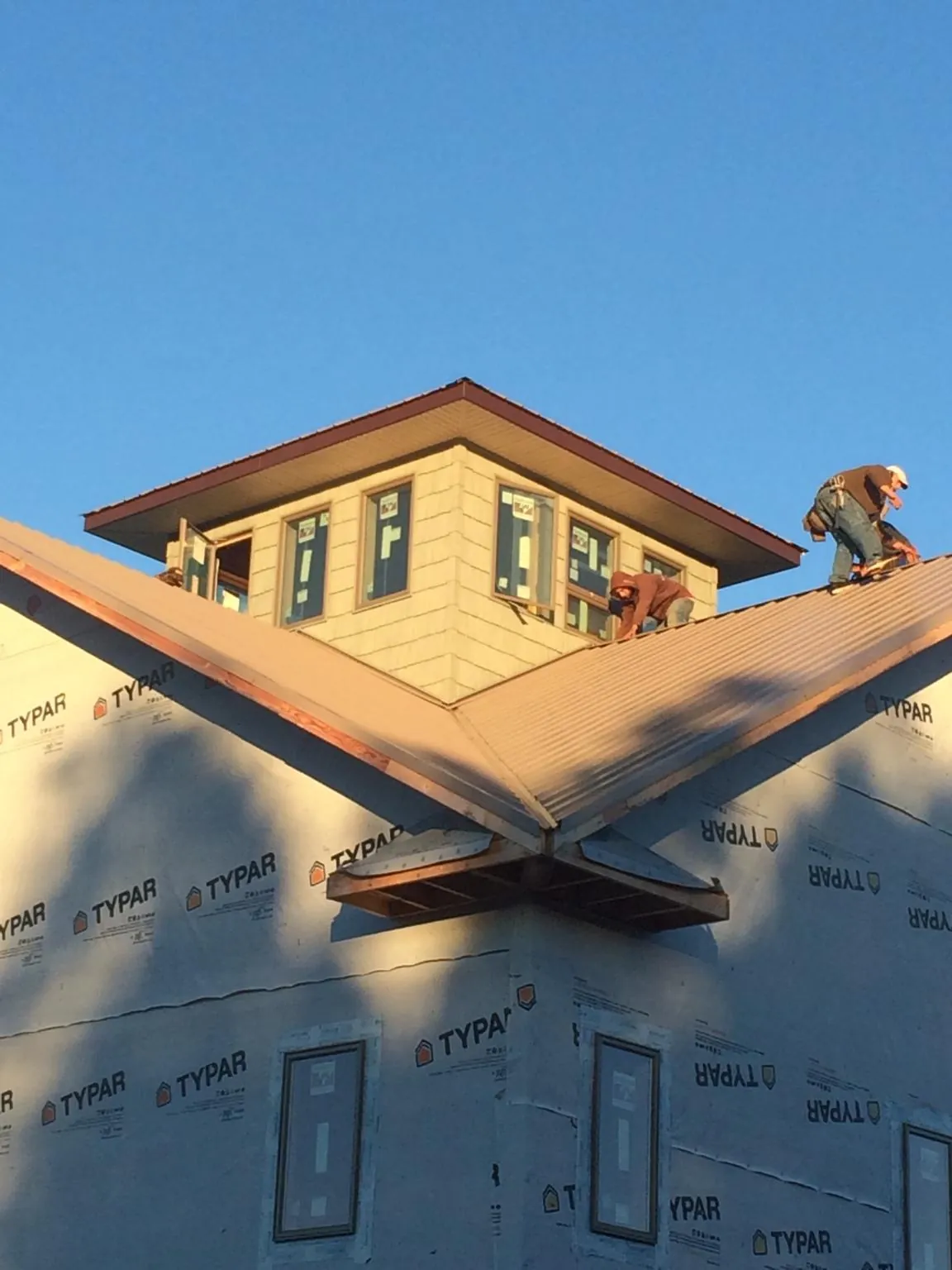 Roofers working around a rooftop cupola on a new metal roof at sunset — Roof Waterproofing in Leadville by Roofing Brothers